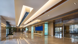 A spacious lobby with a polished marble floor, modern lighting fixtures, and large windows offering views of the outdoors. - Holiday Inn Express Shanghai New Jinqiao by IHG (Shanghai)
