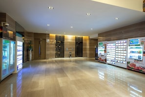 A spacious lobby with a polished floor, vending machines, and a reception area with a glass partition. - Holiday Inn Express Shanghai New Jinqiao by IHG (Shanghai)