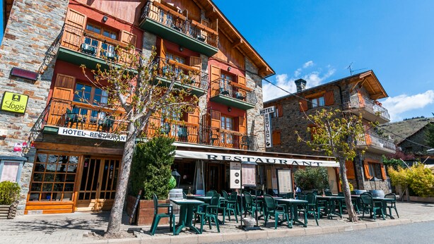 A hotel with outdoor seating and a restaurant sign. - Hotel Esquirol (Llívia)