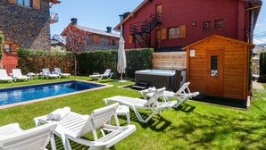 A swimming pool with lounge chairs, a hot tub, and a wooden shed. - Hotel Esquirol (Llívia)