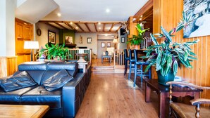 A cozy living room with a leather sofa, wooden dining table, and potted plants. - Hotel Esquirol (Llívia)