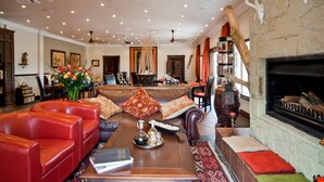 A spacious living room with leather sofas, a coffee table, and a fireplace. - Aquanzi Lodge (Chartwell)