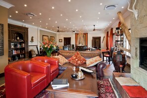 Uma sala de estar ampla com sofás de couro, uma mesa de centro e uma lareira.
