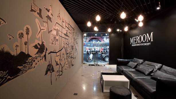 A modern interior with a black leather sofa, a white coffee table, and a mural with various architectural drawings. - Meroom (Phuket)