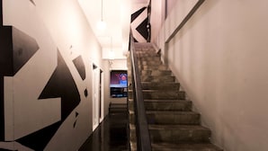 A staircase with a handrail, leading to a room with a large geometric wall design. - Meroom (Phuket)