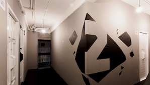 A hallway with a geometric wall design, a door labeled "Guest," and a staircase leading to another area. - Meroom (Phuket)