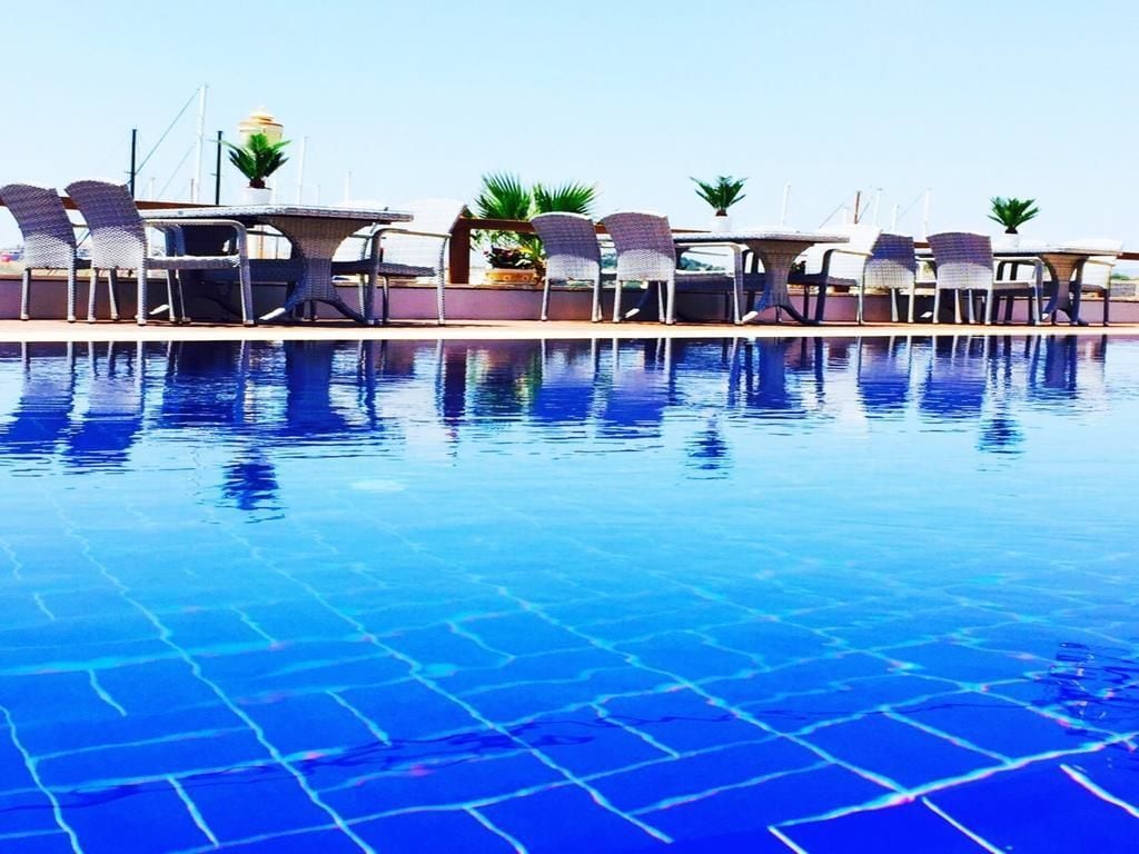 Una piscina al aire libre, sombrillas, tumbonas