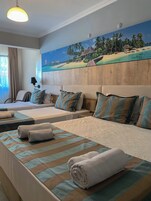 Habitación de hotel con dos camas, un cuadro grande de una playa, una lámpara en el techo y una ventana con cortinas.