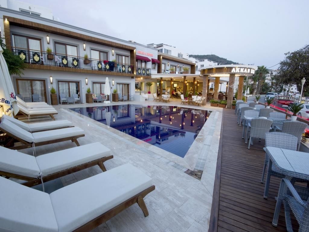 Un hotel con piscina, sillas de descanso y zona de estar al aire libre.