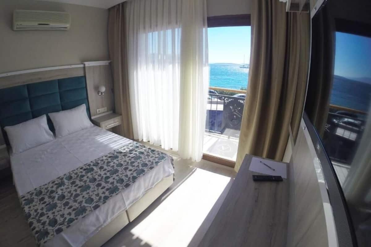 Habitación de hotel con cama, escritorio y ventana grande con vista al mar.