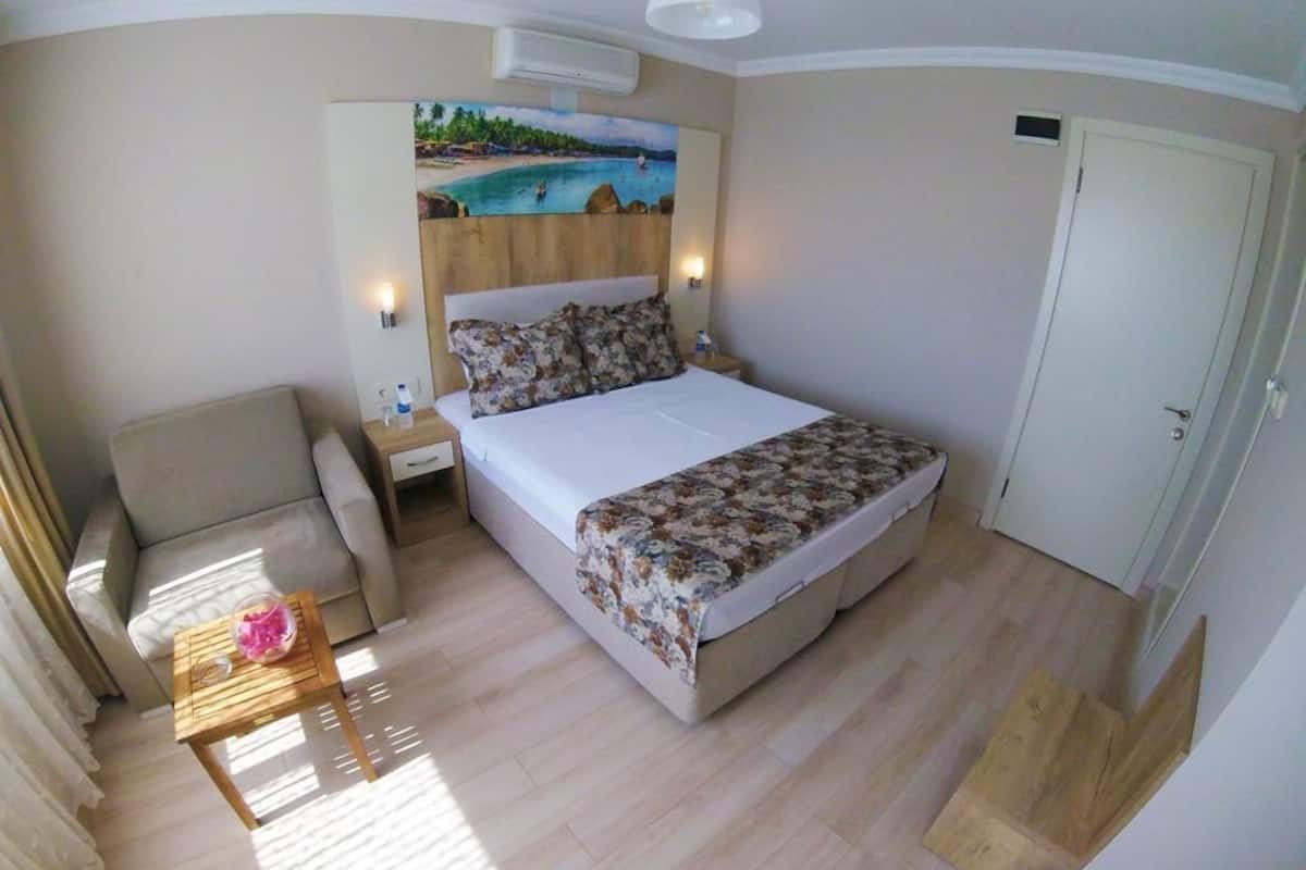 Un dormitorio con cama, mesita de noche, silla y un cuadro de una playa.