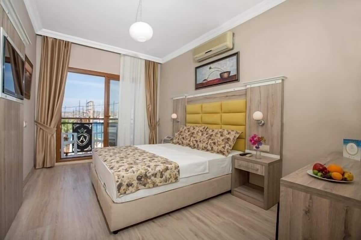 Una habitación de hotel con cama, mesita de noche y un pequeño escritorio con frutero.
