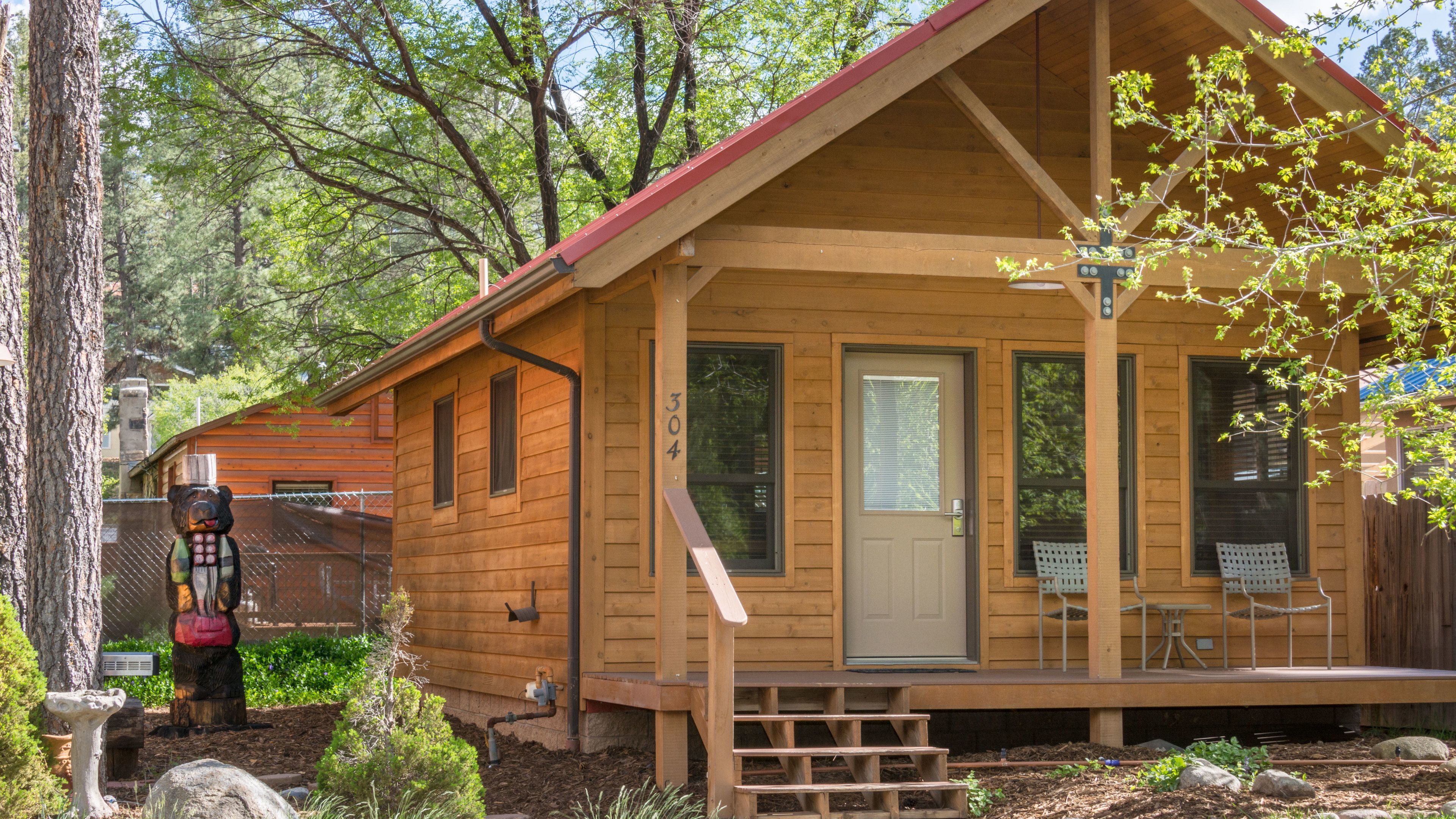 A wooden cabin with a porch, a front door, and a mailbox.