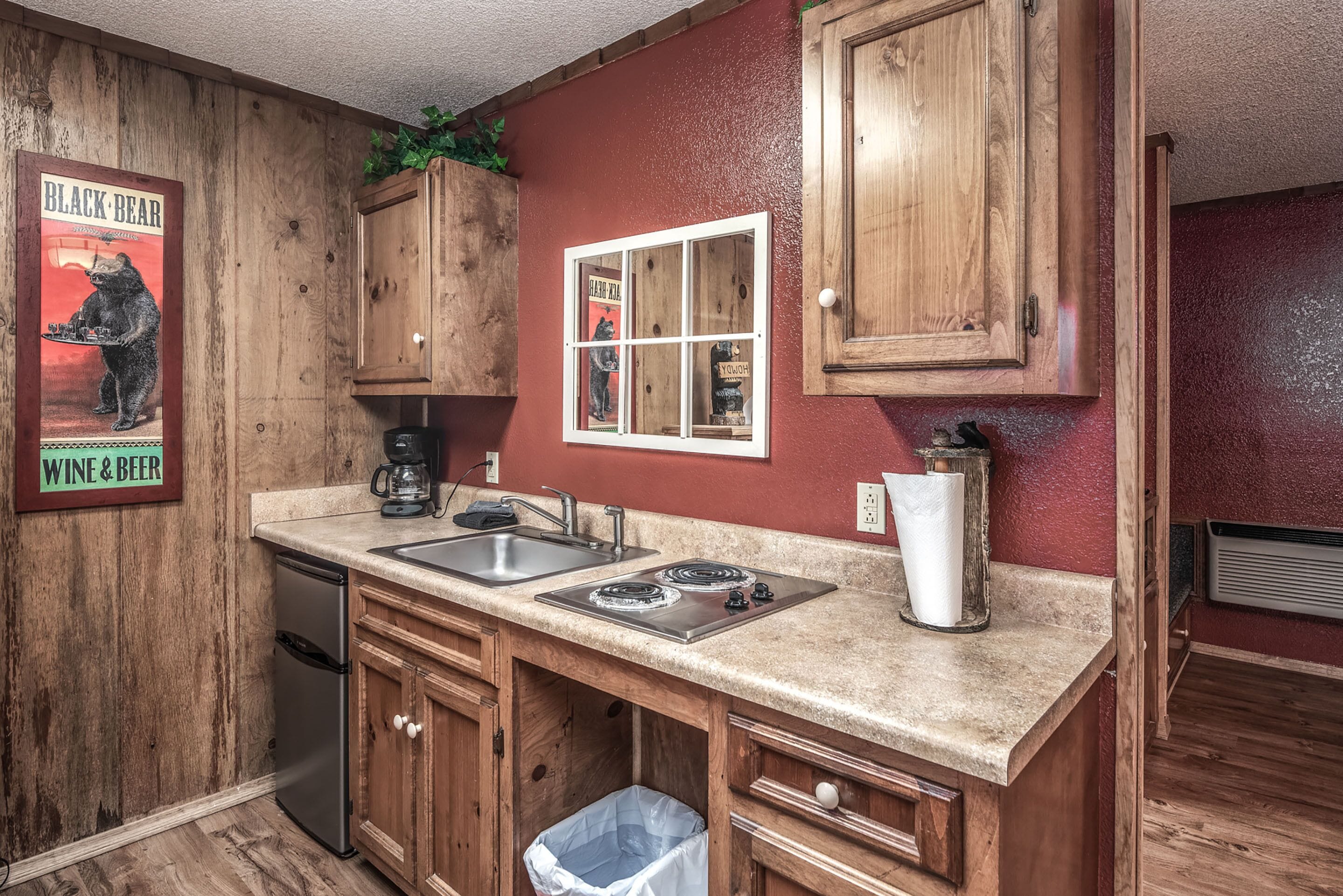A kitchen with wooden cabinets, a double sink, a stove, and a trash can.