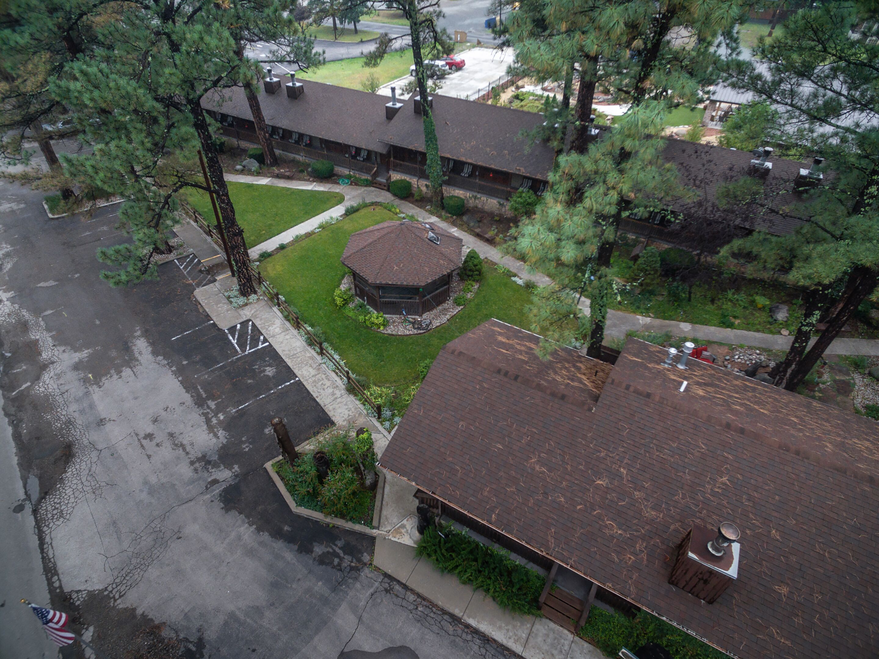 An aerial view of a building with a central courtyard, surrounded by trees and a parking lot.