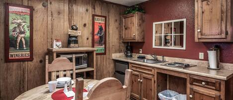 Ein Holzinterieur mit einem Esstisch, Stühlen, einer Mikrowelle, einer Kaffeemaschine und Holzschränken.