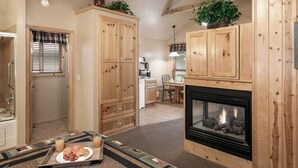 A cozy living room with wooden cabinets, a fireplace, and a dining area. - Shadow Mountain Lodge and Cabins (Ruidoso)