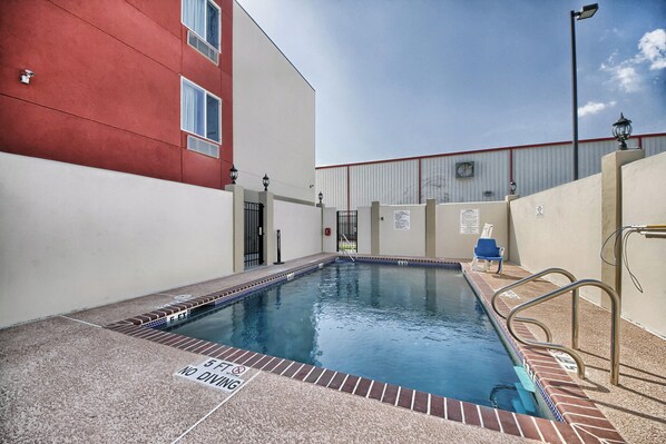 A swimming pool with a no diving sign, a blue chair, and a metal gate. - Motel 6 Weslaco, TX (Weslaco)