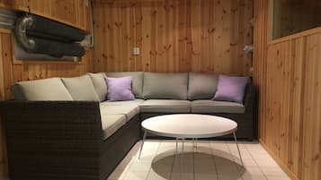 Una habitación con paneles de madera, un sofá modular y una mesa redonda.