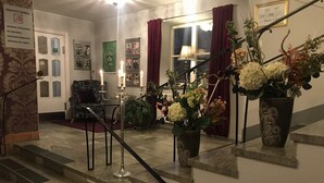 A hotel lobby with a staircase, a chair, a table, and a potted plant. - Hotel Wictoria (Mariestad)