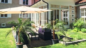 A patio area with outdoor furniture, a large umbrella, and potted plants. - Hotel Wictoria (Mariestad)