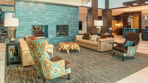 Eine großzügige Lobby mit modernem Design, darunter eine gewölbte Decke, eine Steinwand und eine Sitzecke mit einem gemusterten Teppich.