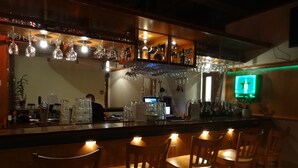 A bar area with wooden chairs, a counter with glasses and bottles, and a television screen. - Botnia Hotel & Restaurant (Kronoby)