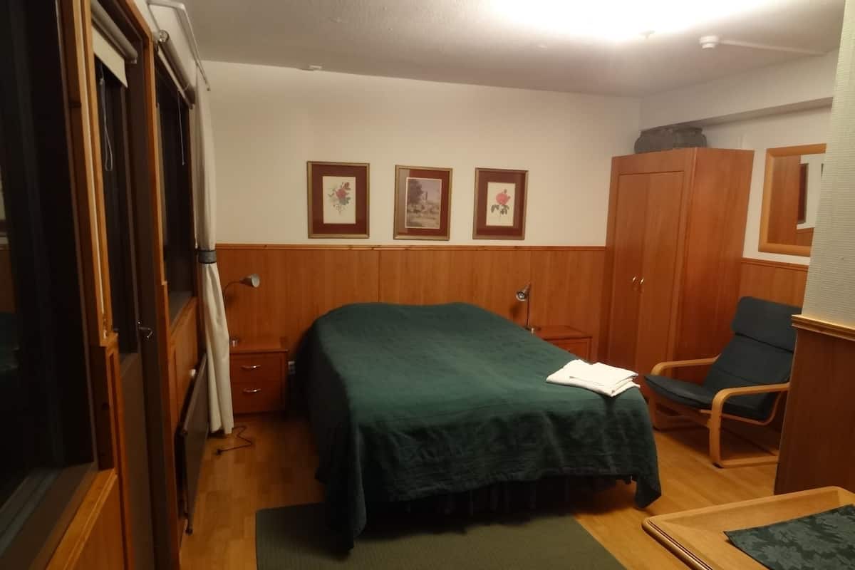 A room with a bed, a chair, a wardrobe, and a desk.