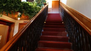 A wooden staircase with red carpeted steps, flanked by dark balusters, leading to a door labeled "PALOIS". - Botnia Hotel & Restaurant (Kronoby)