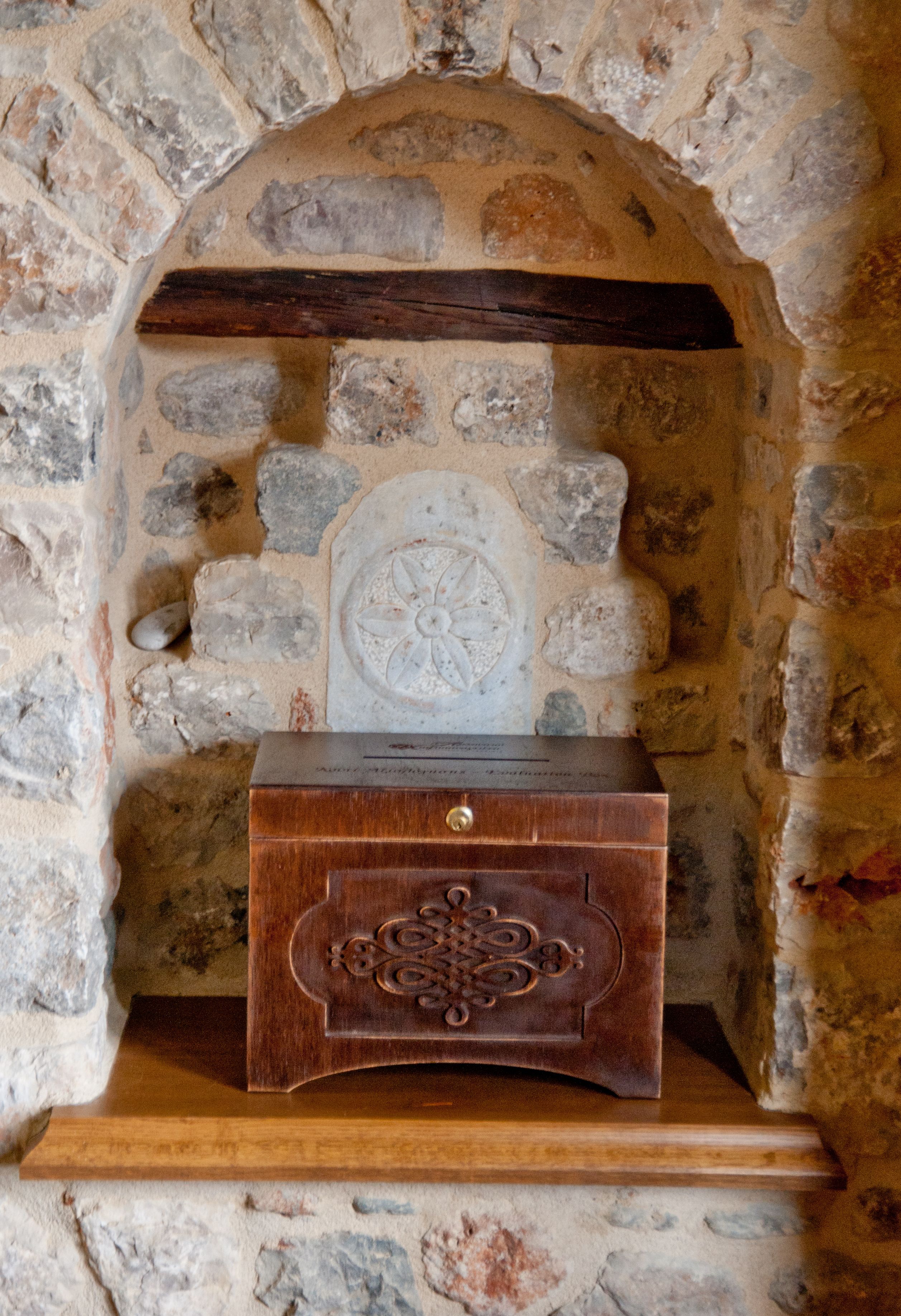 A stone fireplace with a wooden chest and a decorative plate.