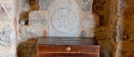A stone fireplace with a wooden chest and a decorative plate.