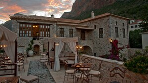 A stone building with a patio area featuring outdoor seating and a fireplace. - Archontiko Hatzipanayiotis (South Kynouria)
