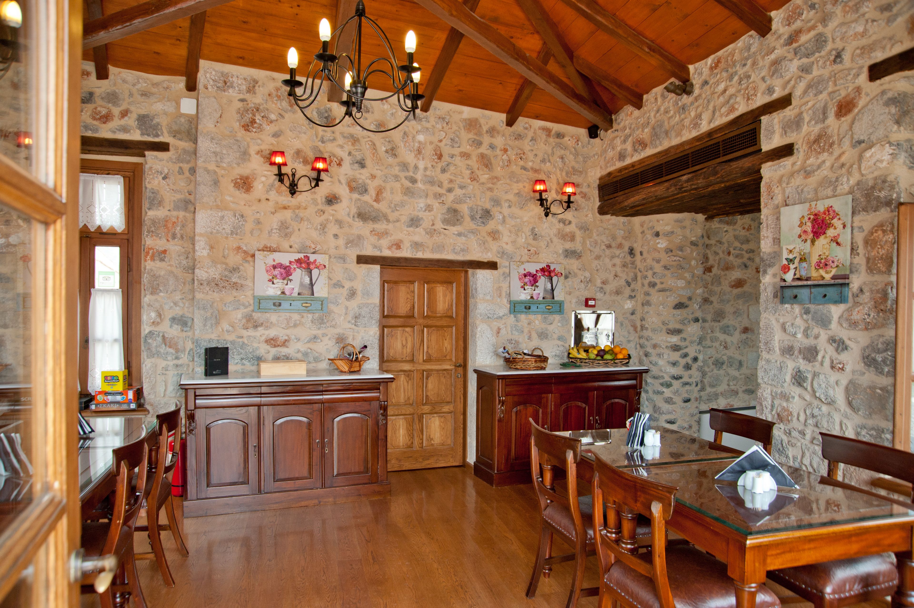 A rustic kitchen with stone walls, wooden cabinets, and a dining area with a glass table and chairs.