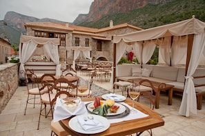 An outdoor dining area with tables and chairs, a sofa, and a canopy. - Archontiko Hatzipanayiotis (South Kynouria)