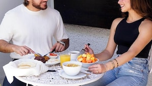 Une table à manger avec des aliments pour le petit-déjeuner, une chemise blanche et un débardeur noir.