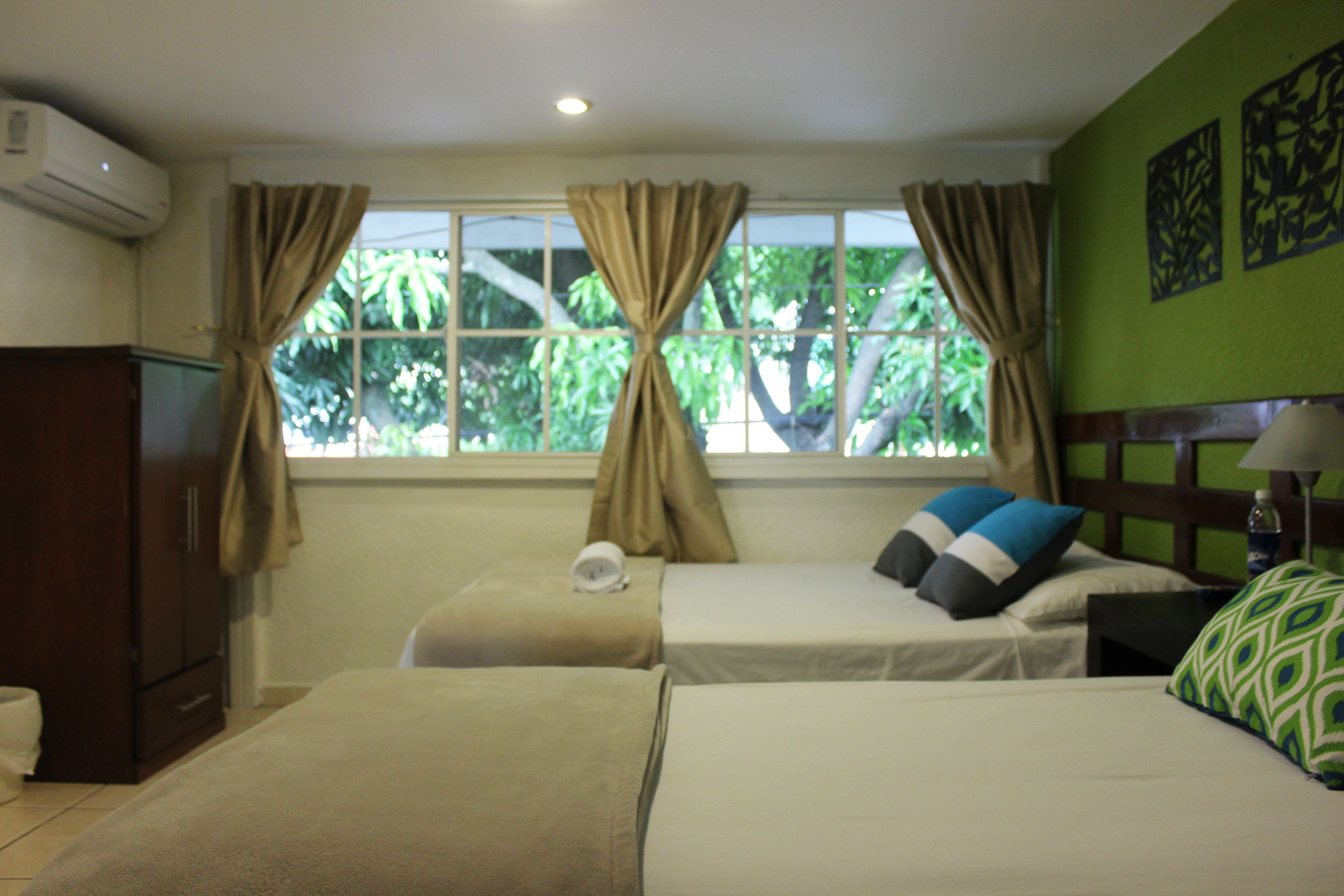 A hotel room with two beds, a wardrobe, and a window with curtains.