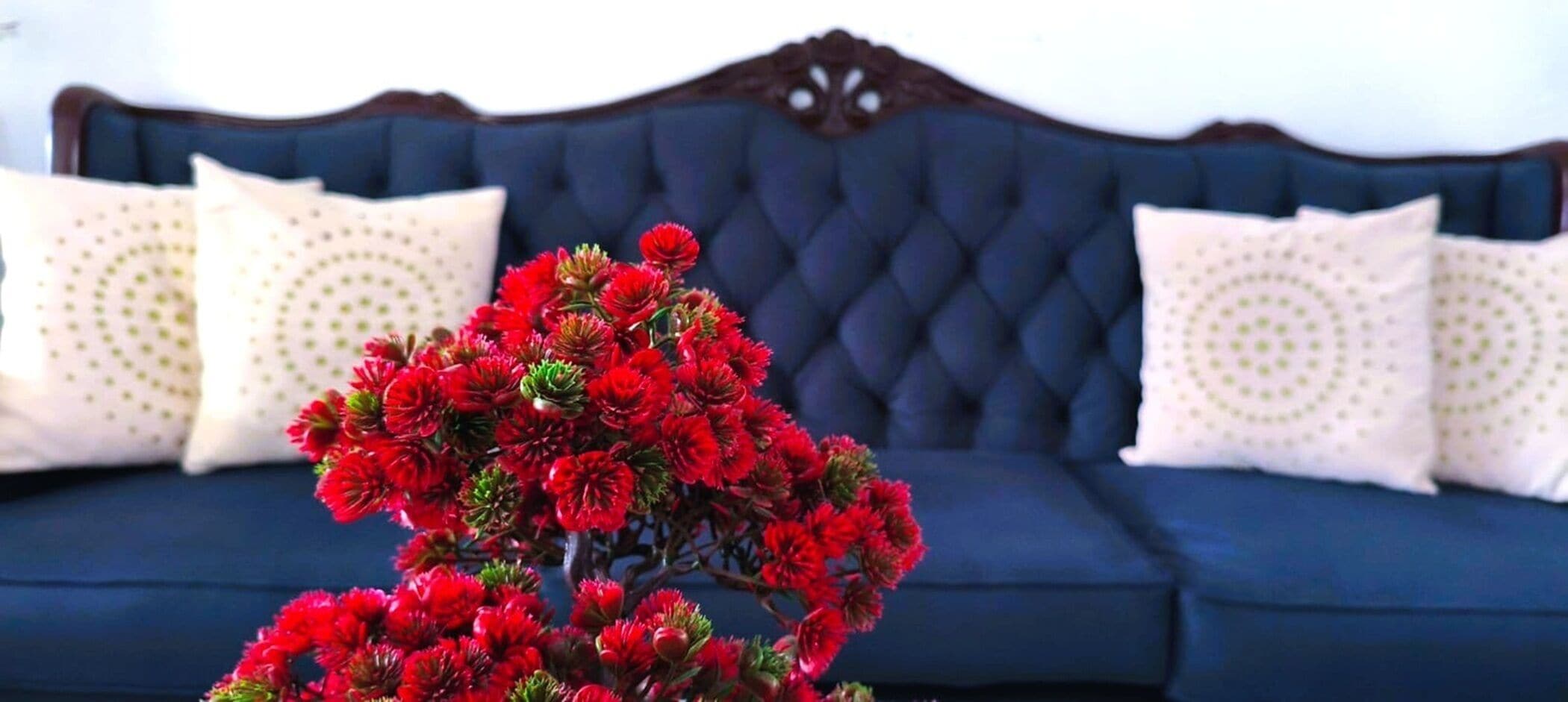 Een donkerblauwe bank met een gestuufde rugleuning en decoratieve houten snijwerk.