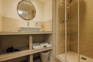 A modern bathroom with a white sink, a round mirror, and a glass-enclosed shower.