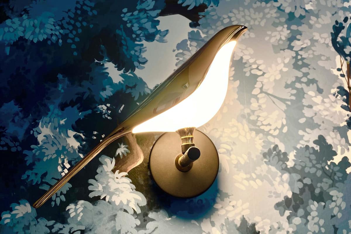 A lamp with a curved neck and a round base, positioned on a surface with a floral pattern.