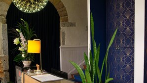 A reception desk with a wooden finish, a yellow lamp, and a potted plant. - HOTELO Lyon Charité (Lyon)