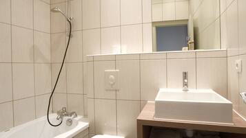 Een moderne badkamer met een badkuip, toilet en wastafel met spiegel.