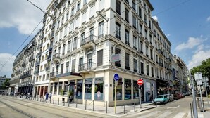 A multi-story hotel with a classic architectural style, featuring balconies and large windows. - HOTELO Lyon Charité (Lyon)