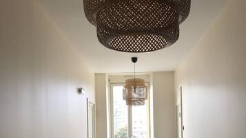 Un escalier recouvert d’une moquette bleue mène à un palier doté d’une grande fenêtre.
