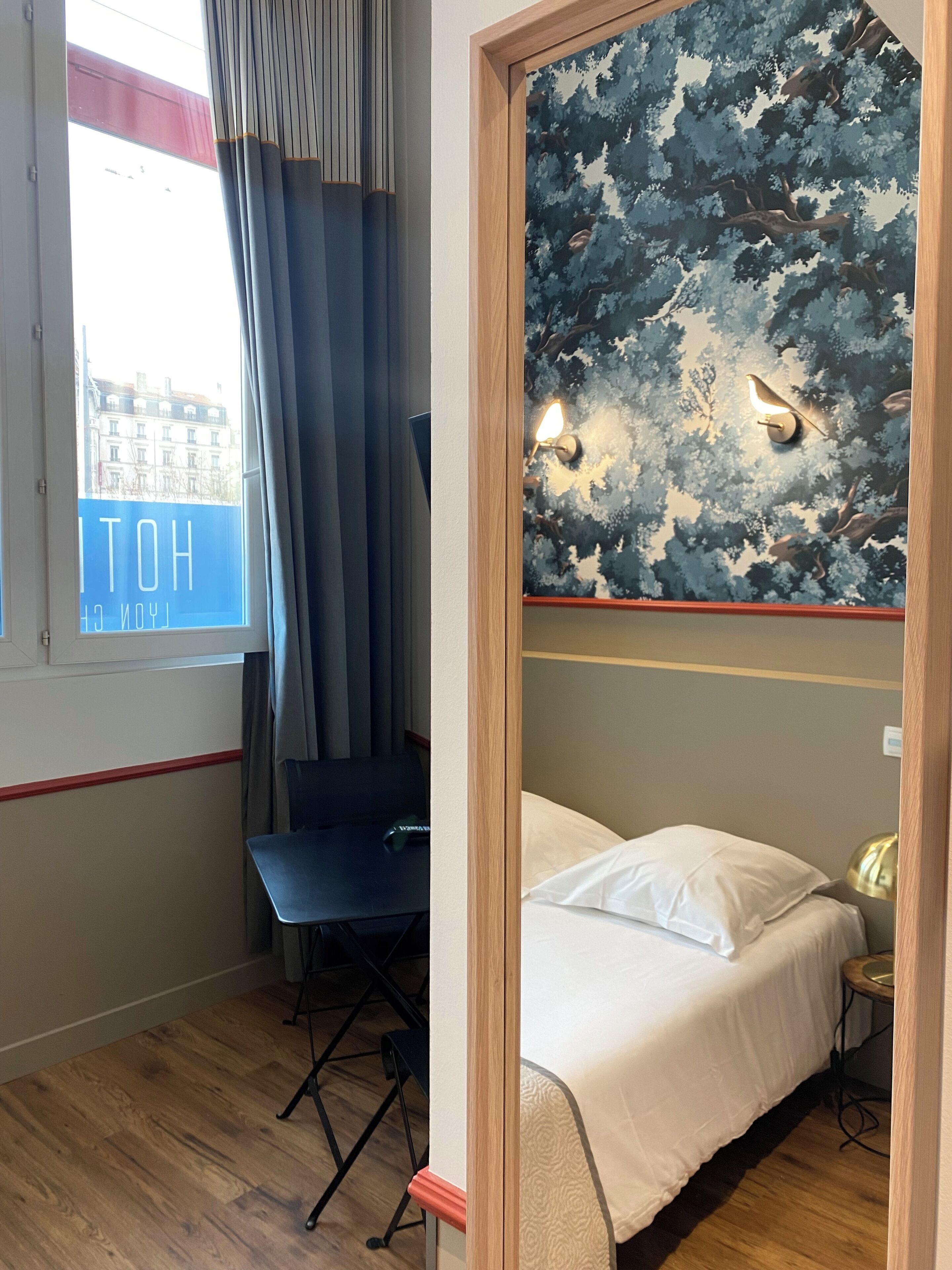 Una habitación de hotel con cama, escritorio y ventana con cortinas.