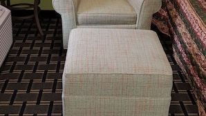 A room with a patterned armchair, a small round table, and a patterned bed. - American Inn (Columbia)