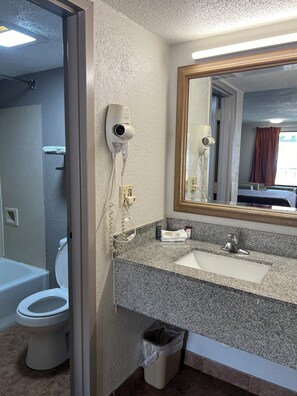 A bathroom with a sink, mirror, and two hair dryers mounted on the wall.