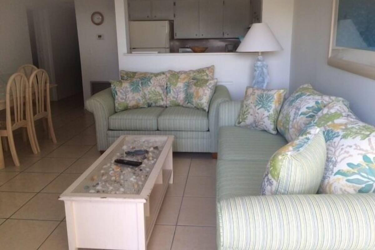 A living room with a sofa, a coffee table, and a dining area with chairs.