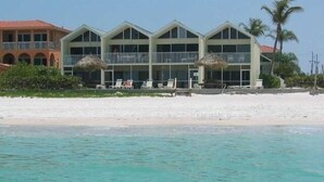 A beachfront hotel with multiple balconies, a sandy beach, and a clear view of the ocean. - Coconuts Beach Resort (Holmes Beach)