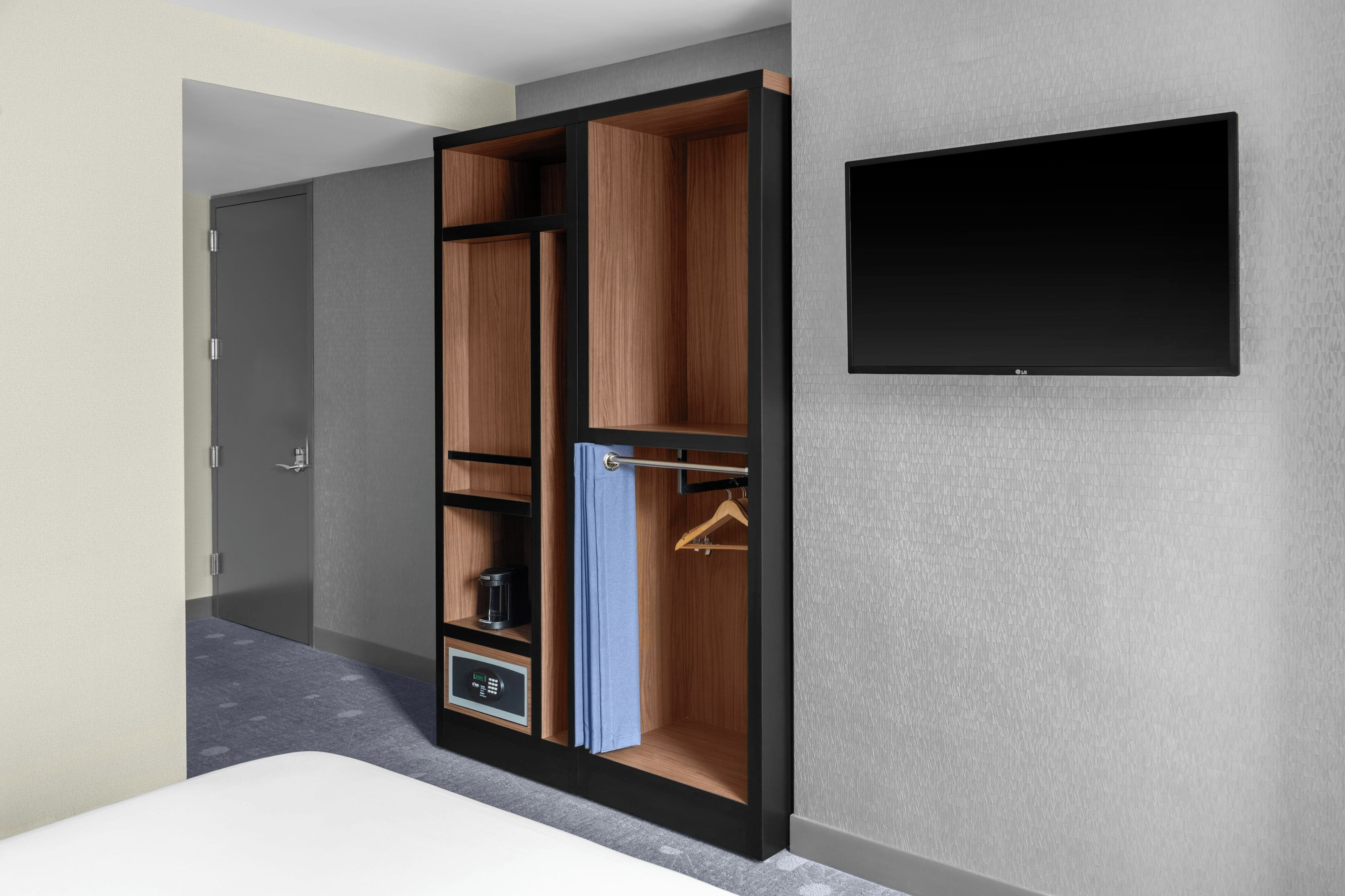 Una habitación moderna con armario, cama y televisor de pantalla plana montado en la pared.