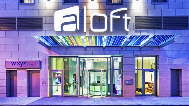 A building with a 'loft' sign, a 'WXYZ lounge' sign, and a revolving door entrance. - Aloft by Marriott Manhattan Downtown - Financial District (New York)
